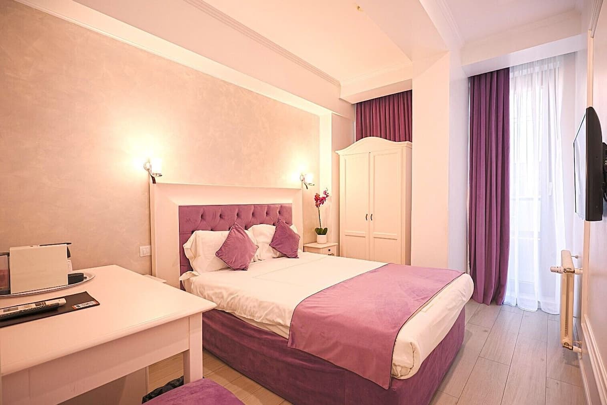 Un dormitorio con cama, mesita de noche y televisor.