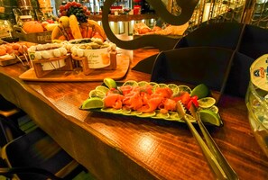 Une table de buffet proposant une variété d’aliments, notamment des fruits, des fromages et du saumon fumé.