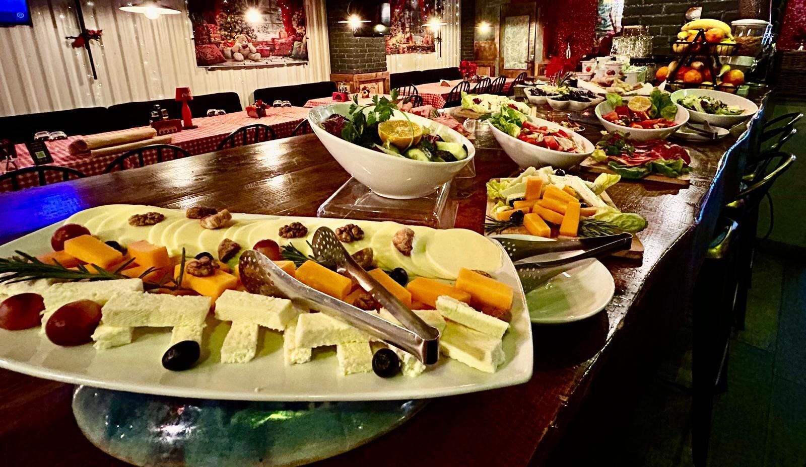 A buffet with various dishes including cheese, fruits, and vegetables.
