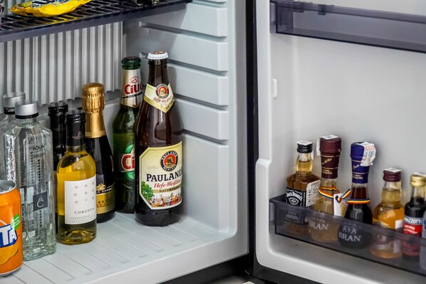 Un refrigerador lleno de diversas bebidas, incluyendo botellas de vino, champán y cerveza.