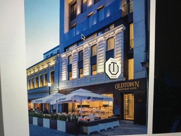 Un hôtel à la façade classique, doté d’un espace extérieur aménagé et d’une enseigne bien visible indiquant « Oldtown Boutique Hotel ».