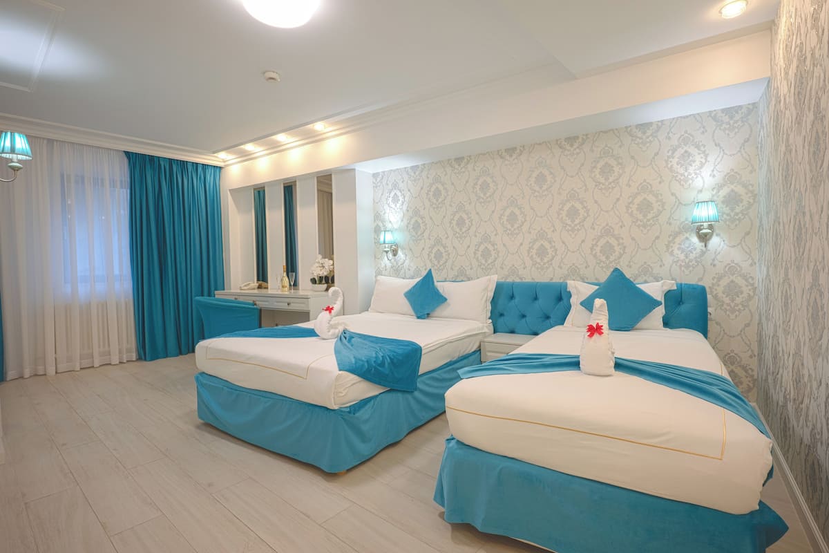 Habitación de hotel con dos camas, un tocador y un espejo.