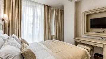 Una habitación de hotel con una cama, un escritorio, un televisor y cortinas.