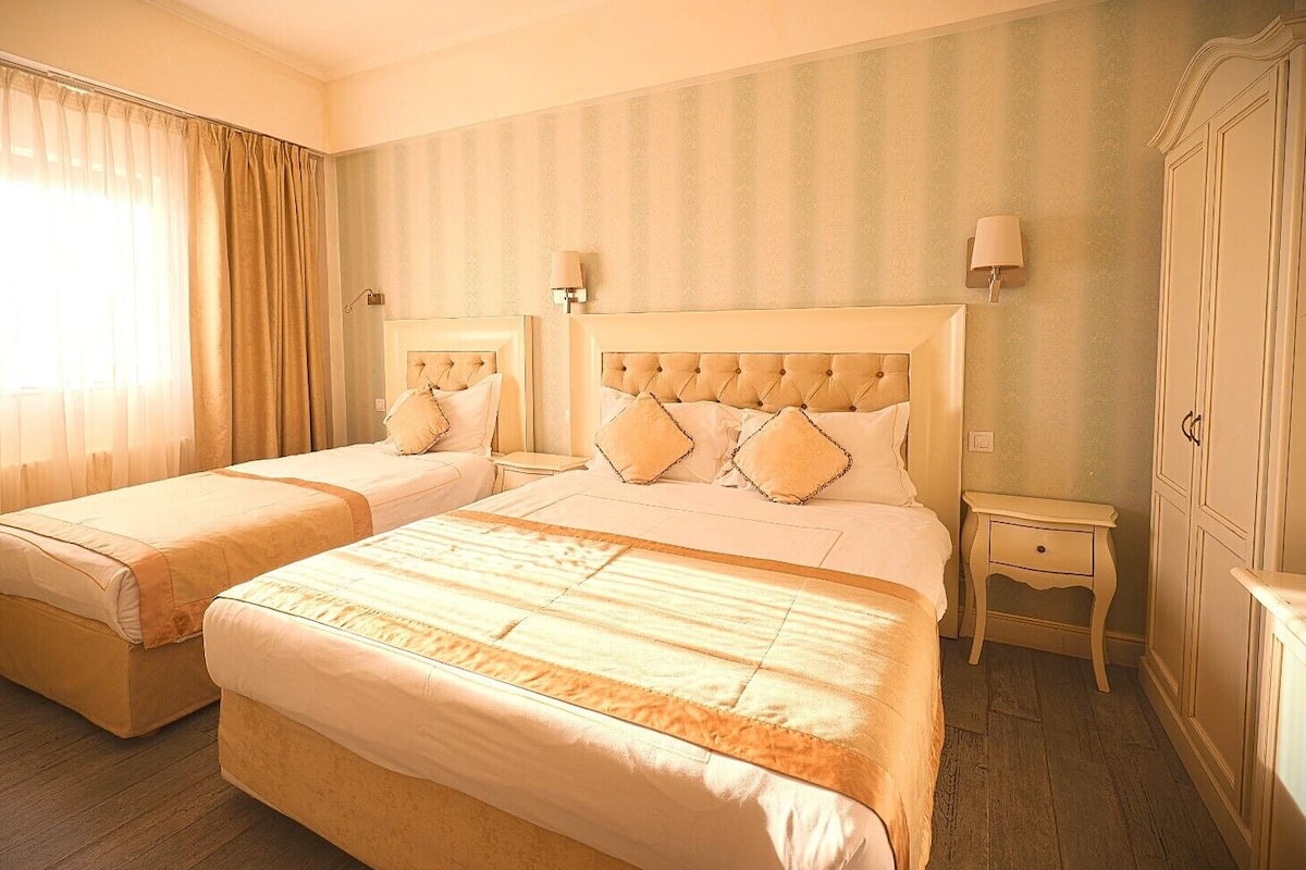 Una habitación de hotel con dos camas, una mesita de noche, una lámpara y un armario.