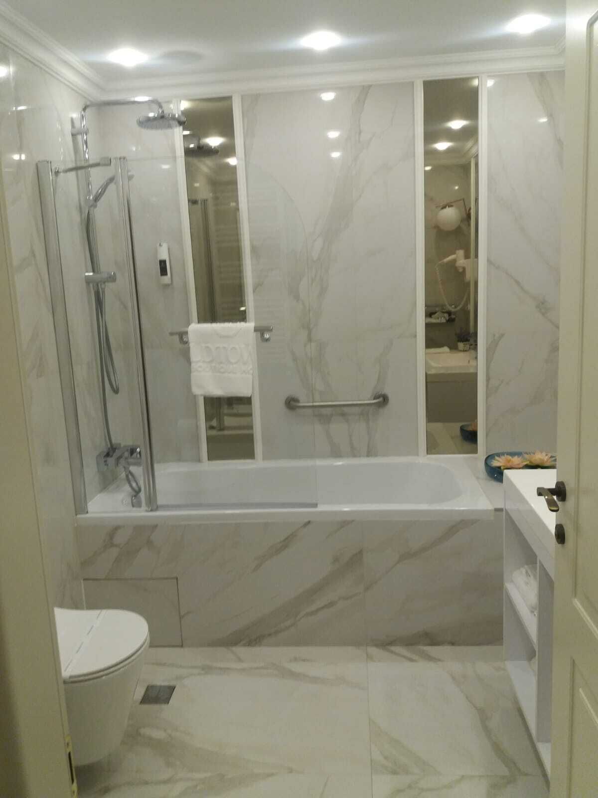 Un baño moderno con ducha envuelta en vidrio, una bañera independiente y un inodoro.