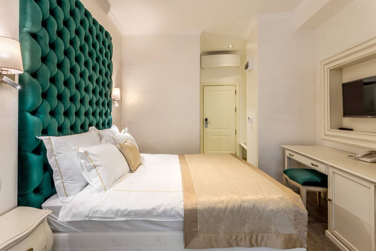 Una habitación de hotel ordenada, con una cama grande, un escritorio, un televisor y una puerta que da a otra estancia.