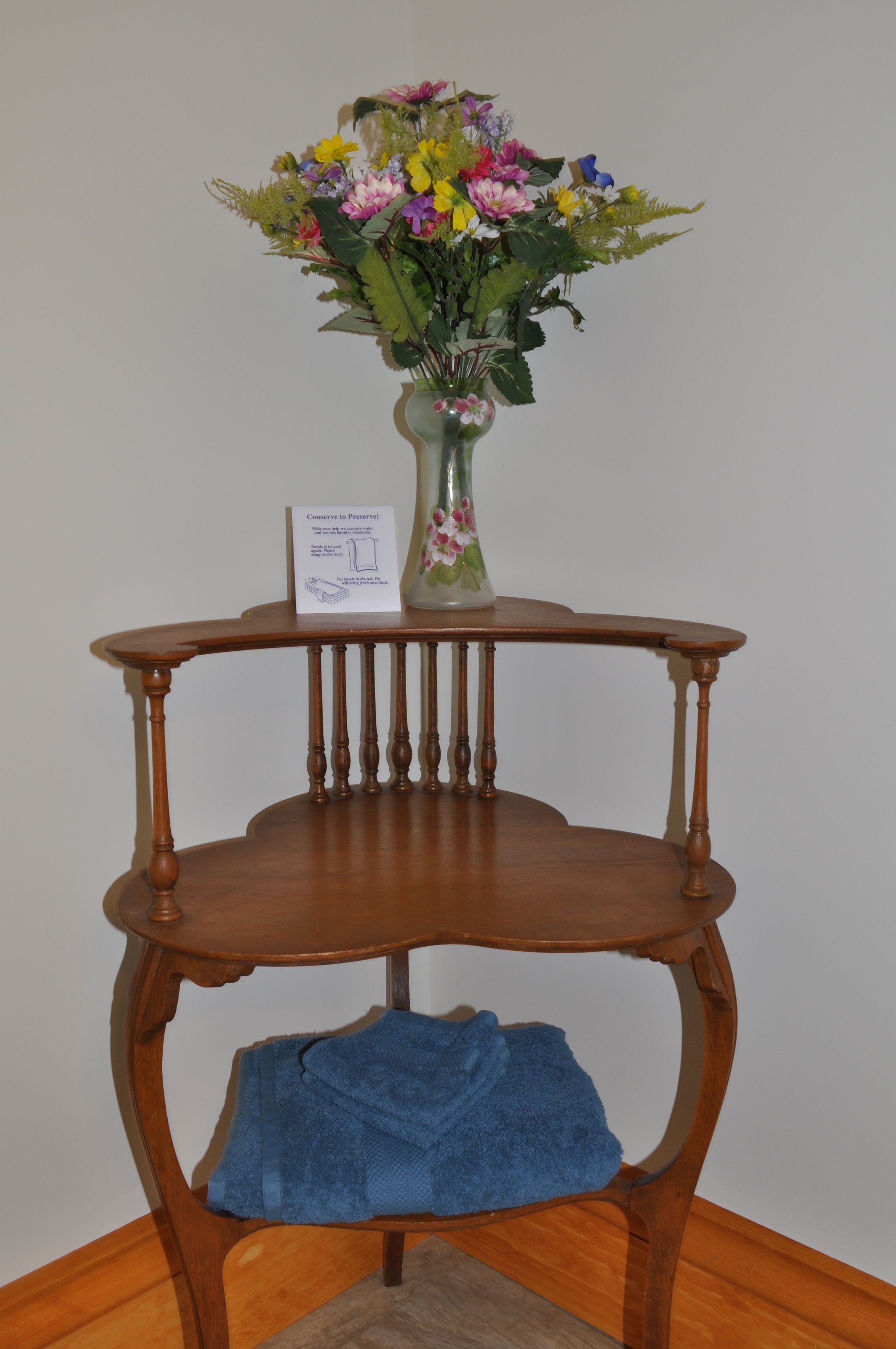 A wooden table with a vase of flowers and a blue towel on it.