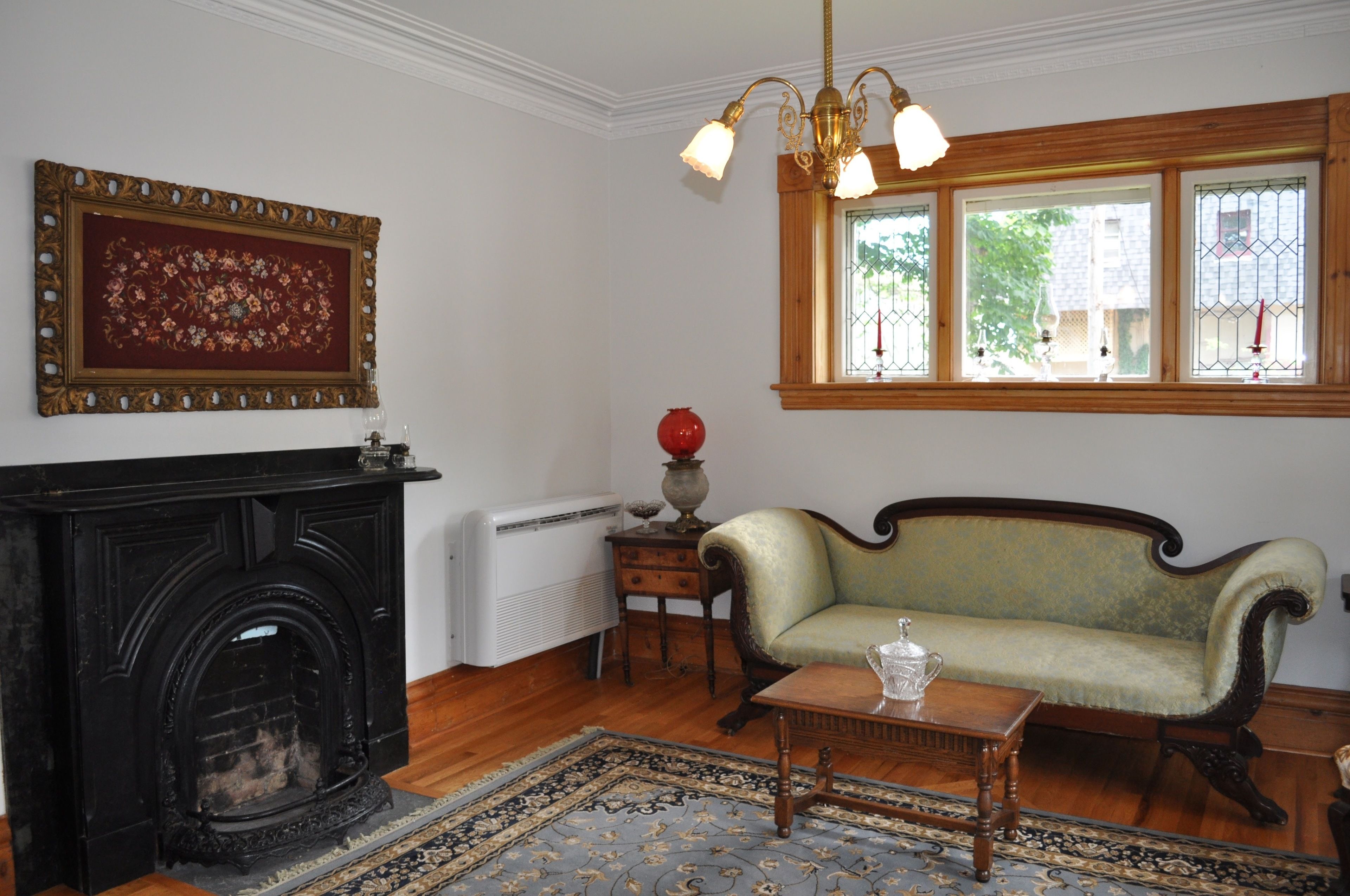 A room with a fireplace, a sofa, a table, and a window with a view.