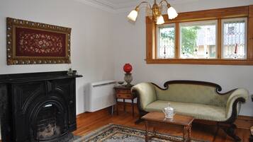 A room with a fireplace, a sofa, a table, and a window with a view.