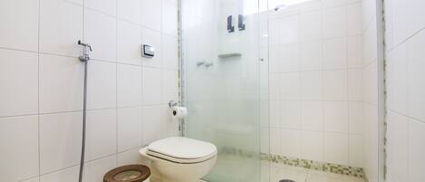 A bathroom with a toilet, shower, and glass-enclosed shower stall.