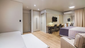 Habitación de hotel con dos camas, un escritorio, una silla, un televisor y aire acondicionado.