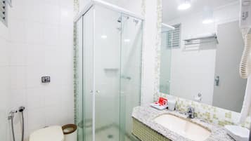 A bathroom with a glass-enclosed shower, a toilet, a sink, and a hairdryer.