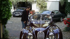 A vintage car parked in a driveway with a house in the background. - Hotel Schlossgarten (Neustrelitz)