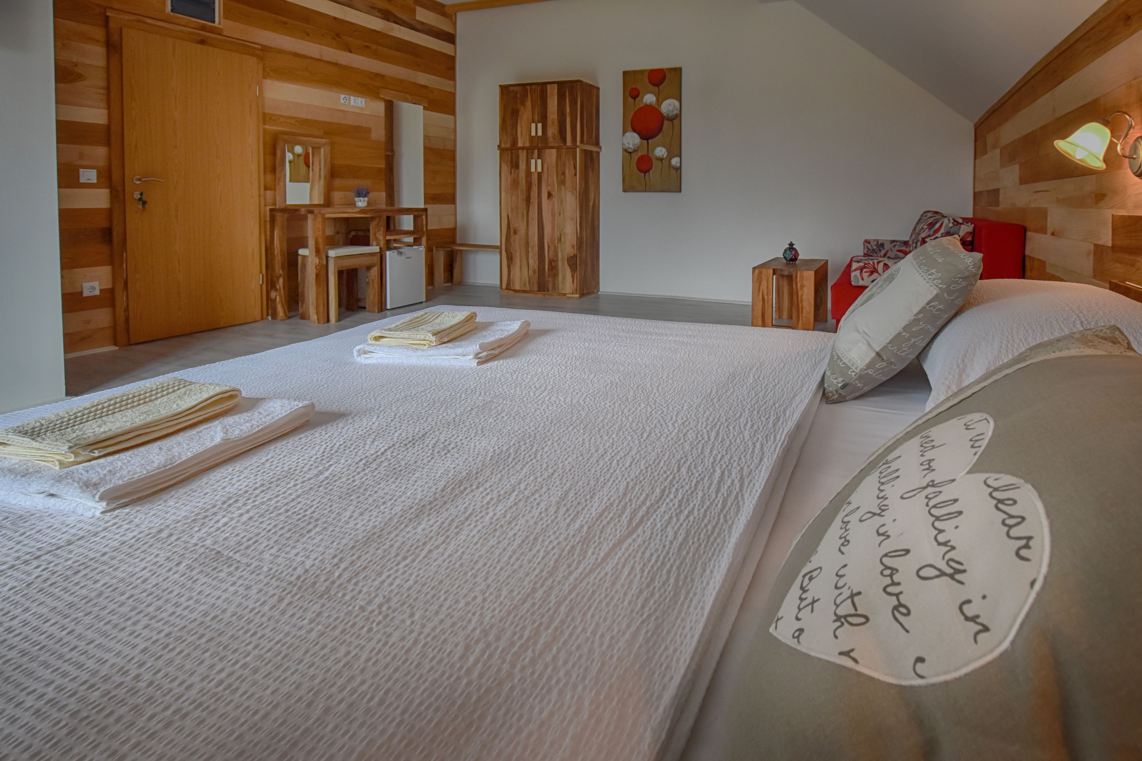 A cozy bedroom with a large bed, wooden wardrobe, and a small desk.