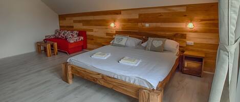 A bedroom with a wooden headboard, a red sofa, a wooden bed frame, and two bedside tables.