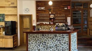 A bar area with a stone counter, wooden shelves with glasses, a clock, and a 'HOME' sign.