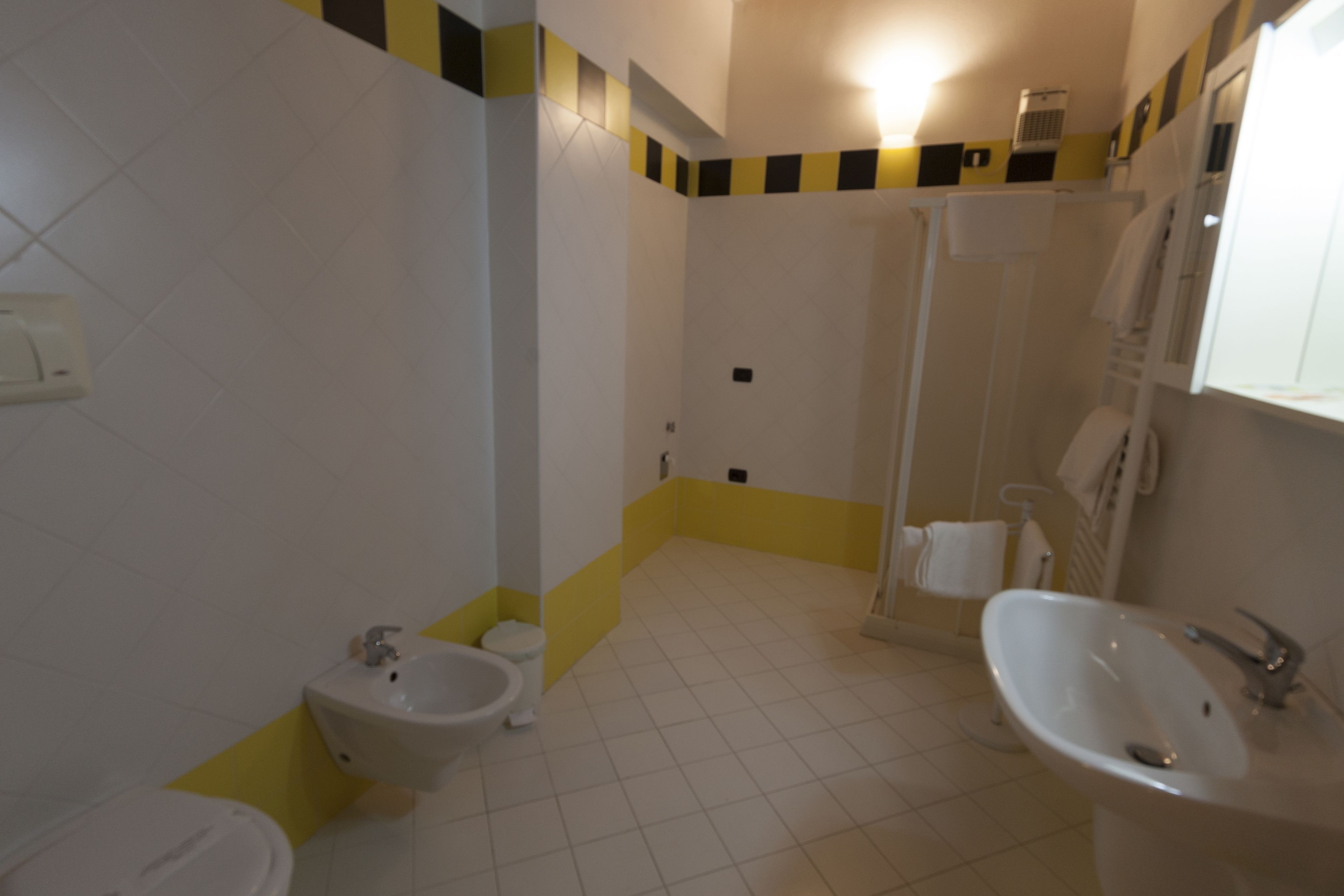 A bathroom with a toilet, bidet, sink, and shower.