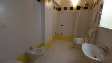 A bathroom with a toilet, bidet, sink, and shower.
