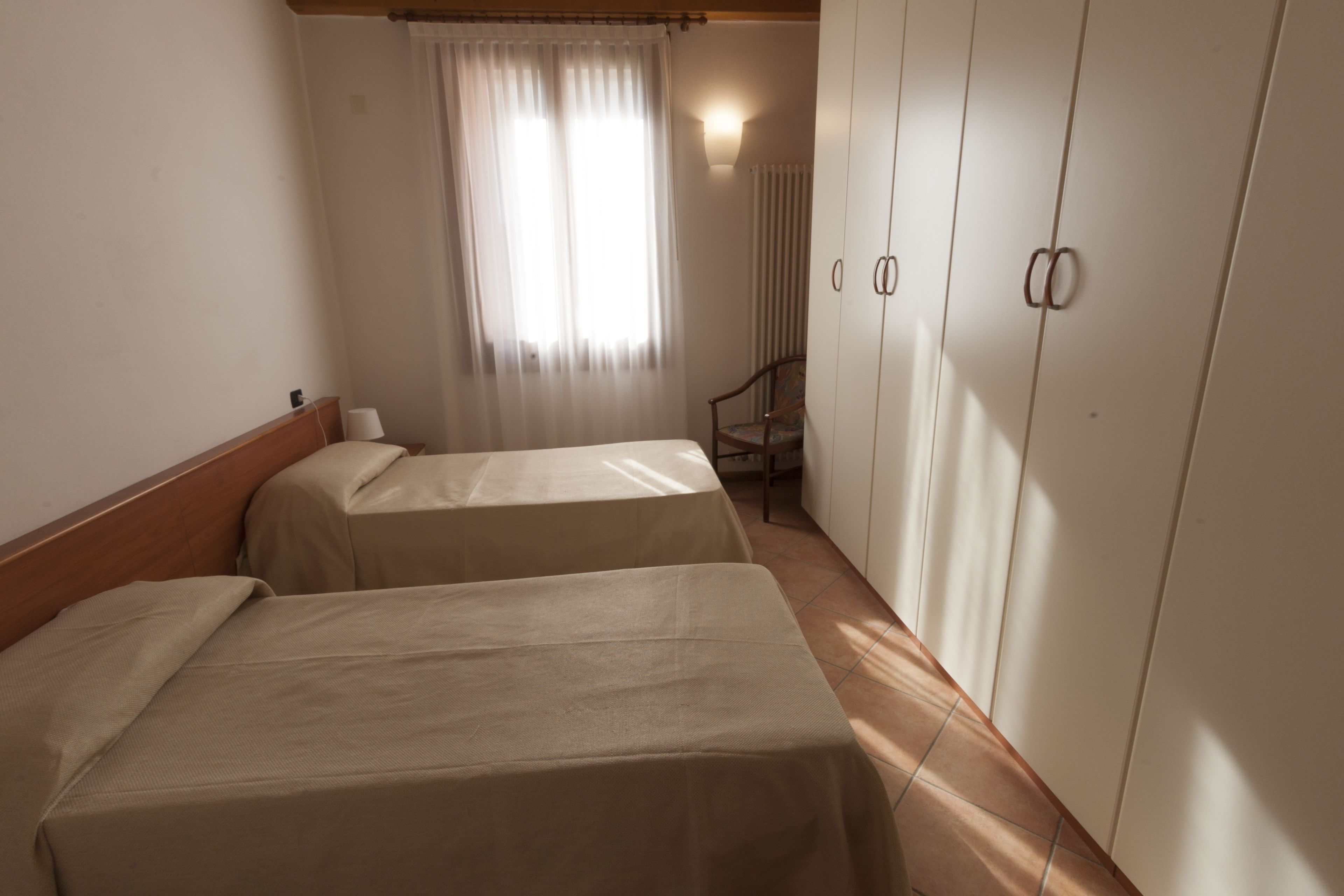Una habitación con dos camas, una silla y un armario.