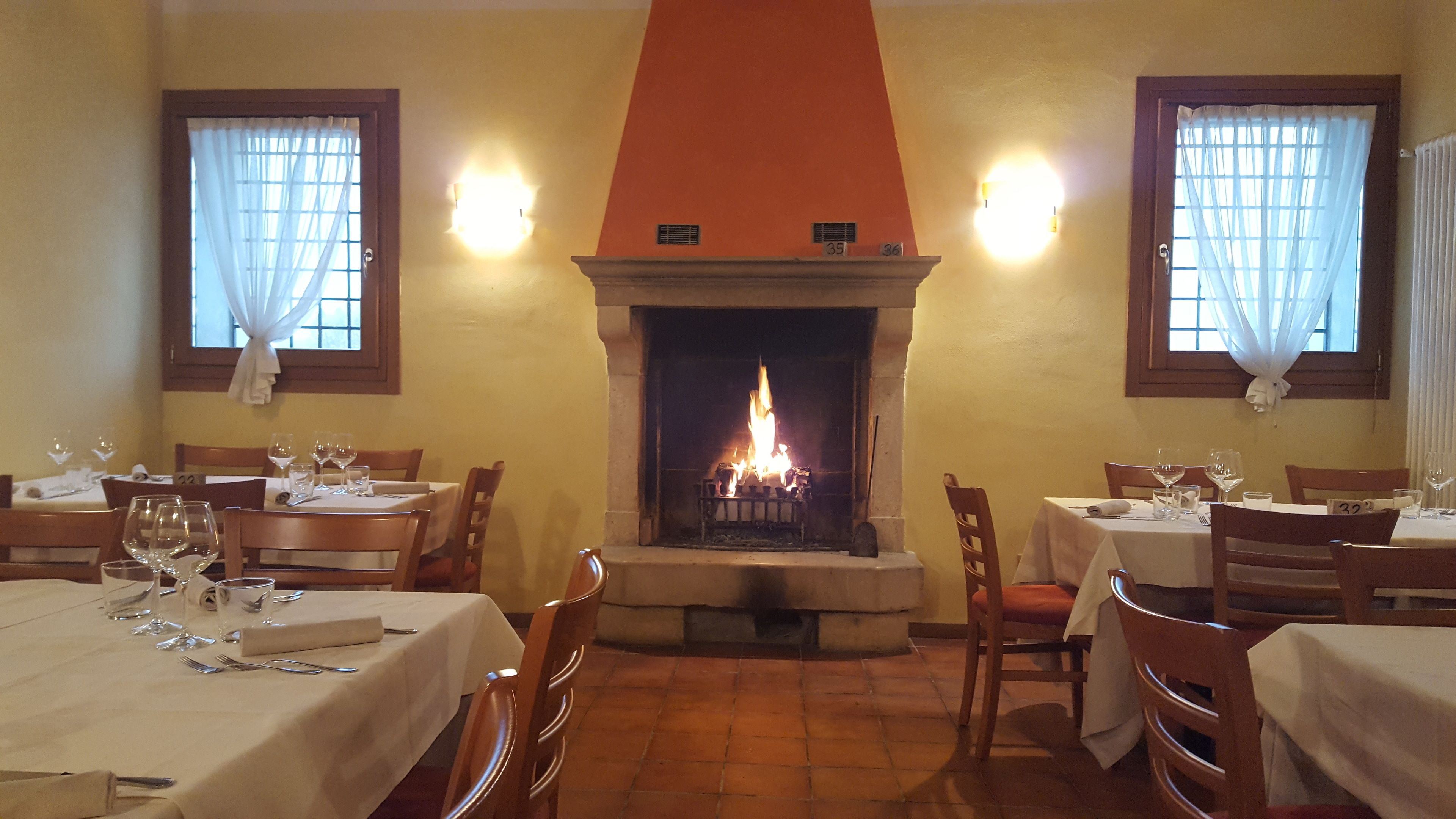 Un ristorante con camino, tavoli e sedie in legno.