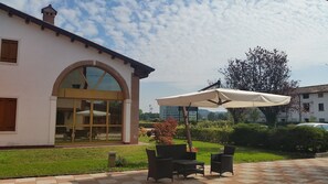 A patio area with outdoor furniture and a large umbrella. - Locanda Veneta (Vicenza)