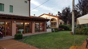 Un restaurante con terraza al aire libre, una cubierta de madera y un césped bien cuidado.