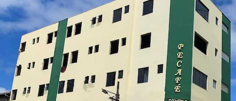 Un hotel a più piani con facciata verde e bianca, numerose finestre e un ingresso ben visibile.