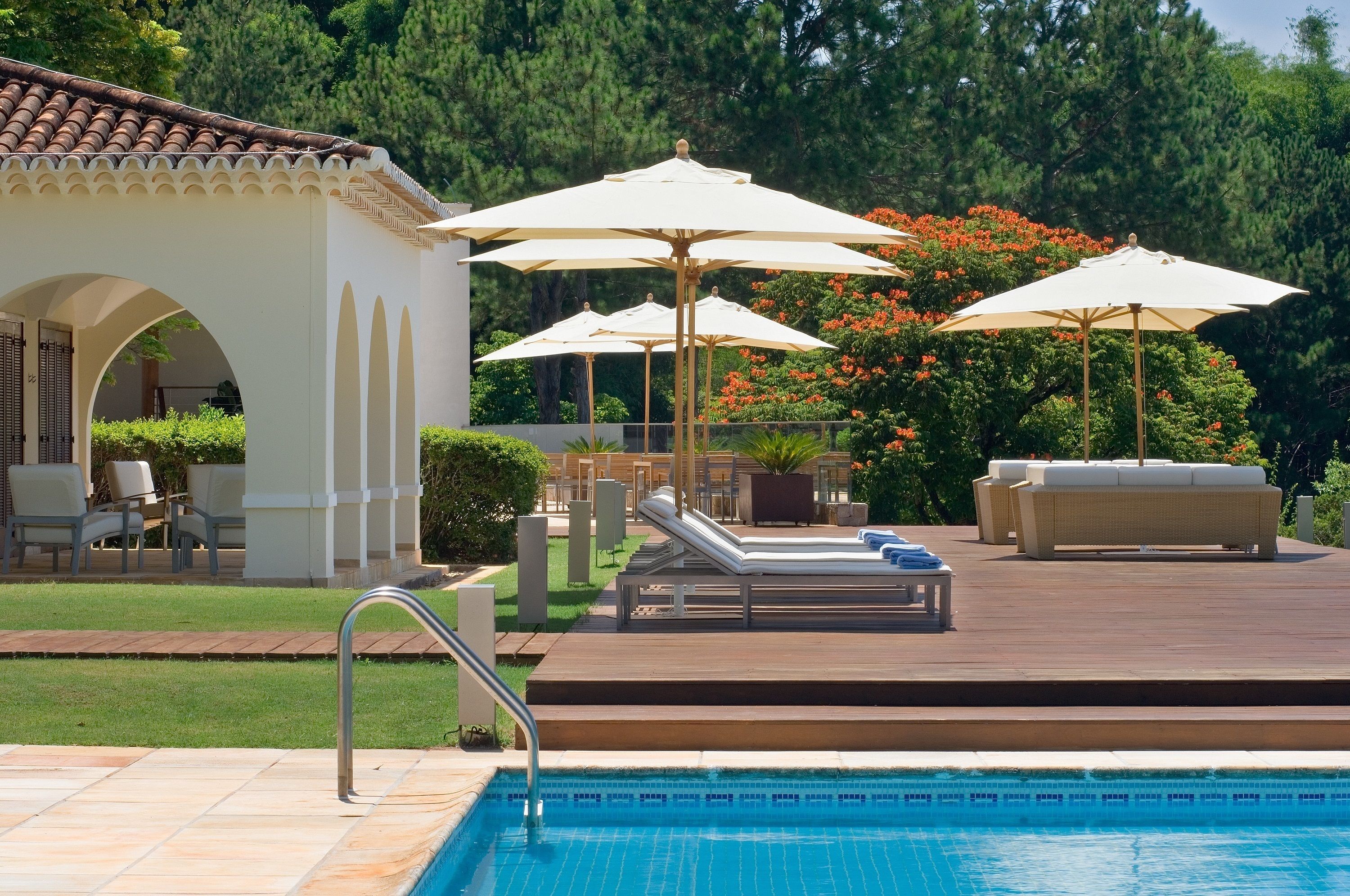 A poolside area with lounge chairs, umbrellas, and a small patio with seating.
