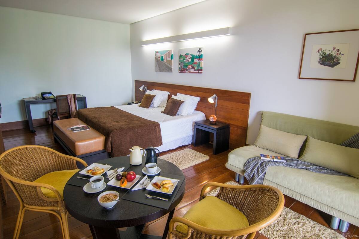Une chambre d’hôtel comprenant un lit, une table de chevet, une lampe et un coin repas avec une table mise pour le petit-déjeuner.
