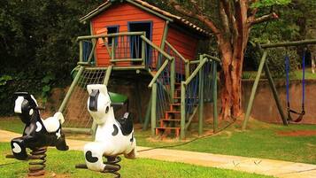 Children can play and explore in this outdoor play area featuring a playhouse with a staircase and swings.