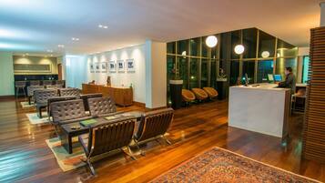 Un moderno vestíbulo de hotel con mostrador de recepción, zona de estar y un gran ventanal con vistas al exterior.