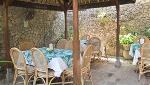An outdoor patio with stone walls and wicker furniture. - Poppies Bali Hotel (Kuta)