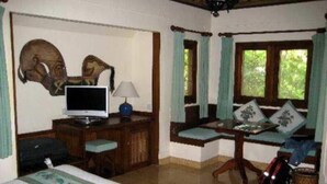 A room with a bed, a desk with a computer, a chair, and a window with curtains. - Poppies Bali Hotel (Kuta)