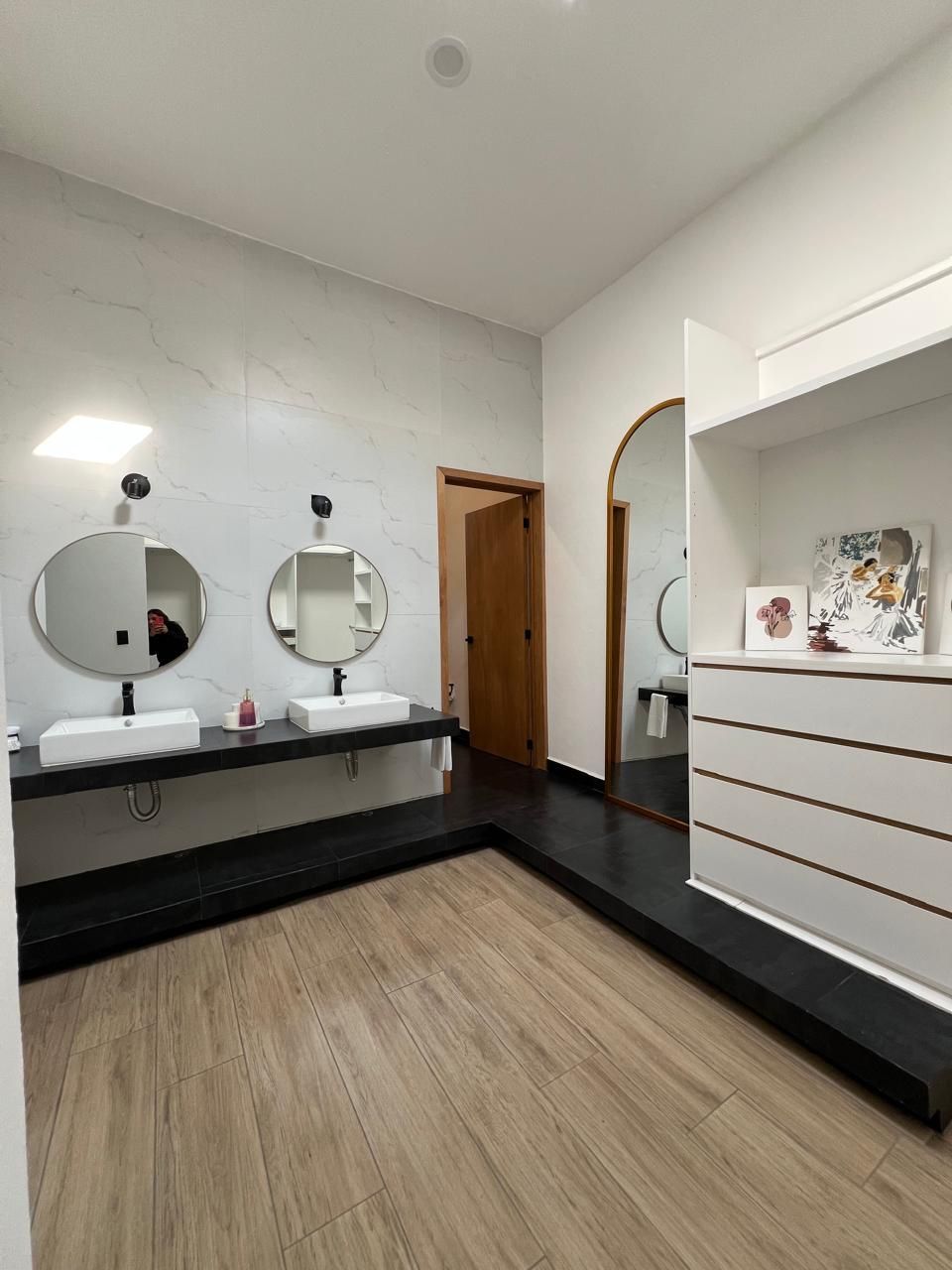 Un bany modern amb dues dutxes, un mirall i una porta de fusta.