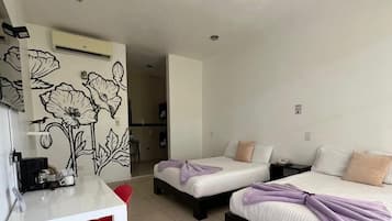 Una habitación de hotel con dos camas, un escritorio pequeño y una kitchenette.