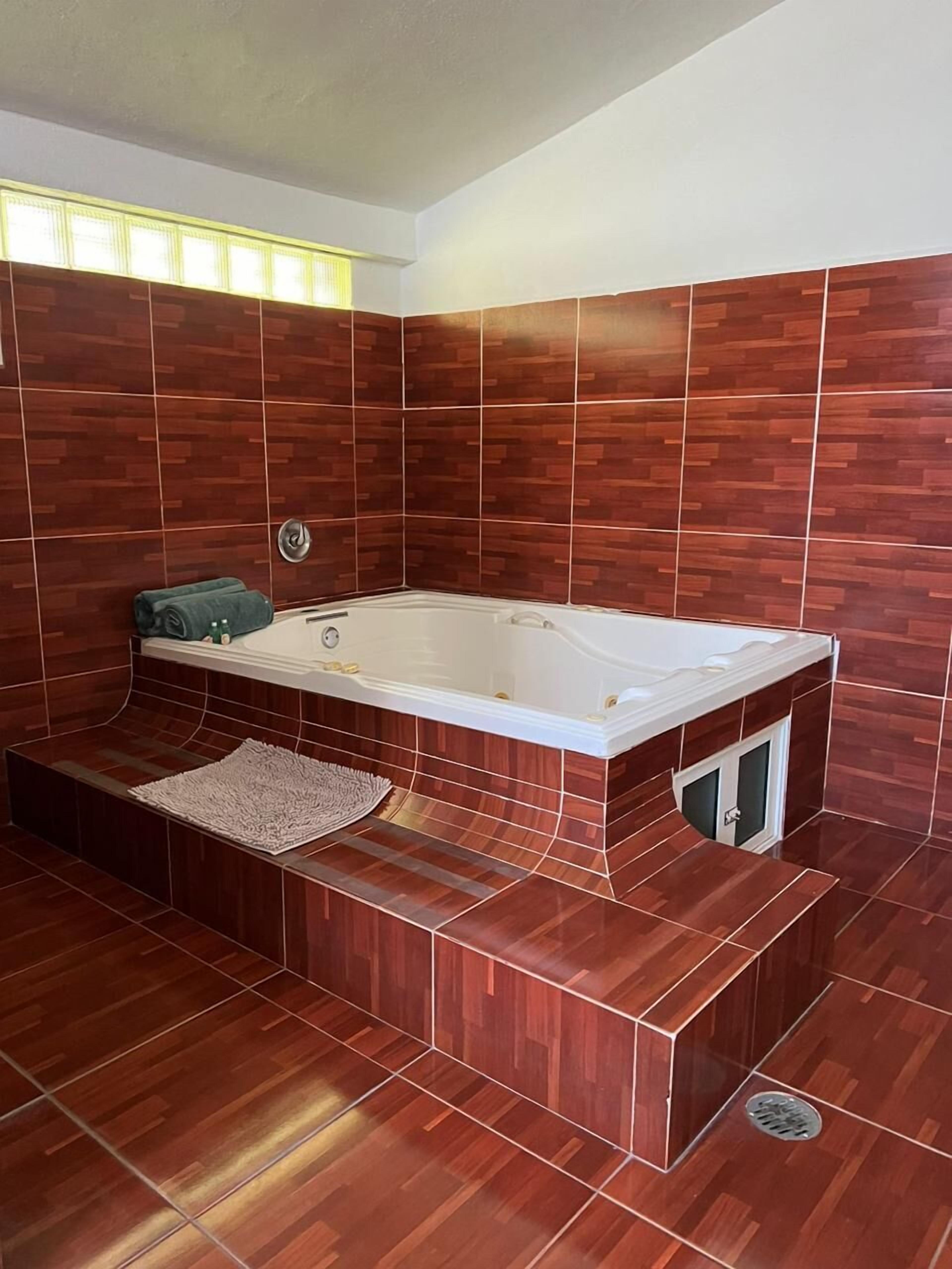 Un baño moderno con suelo de madera, una bañera grande y un banco empotrado.