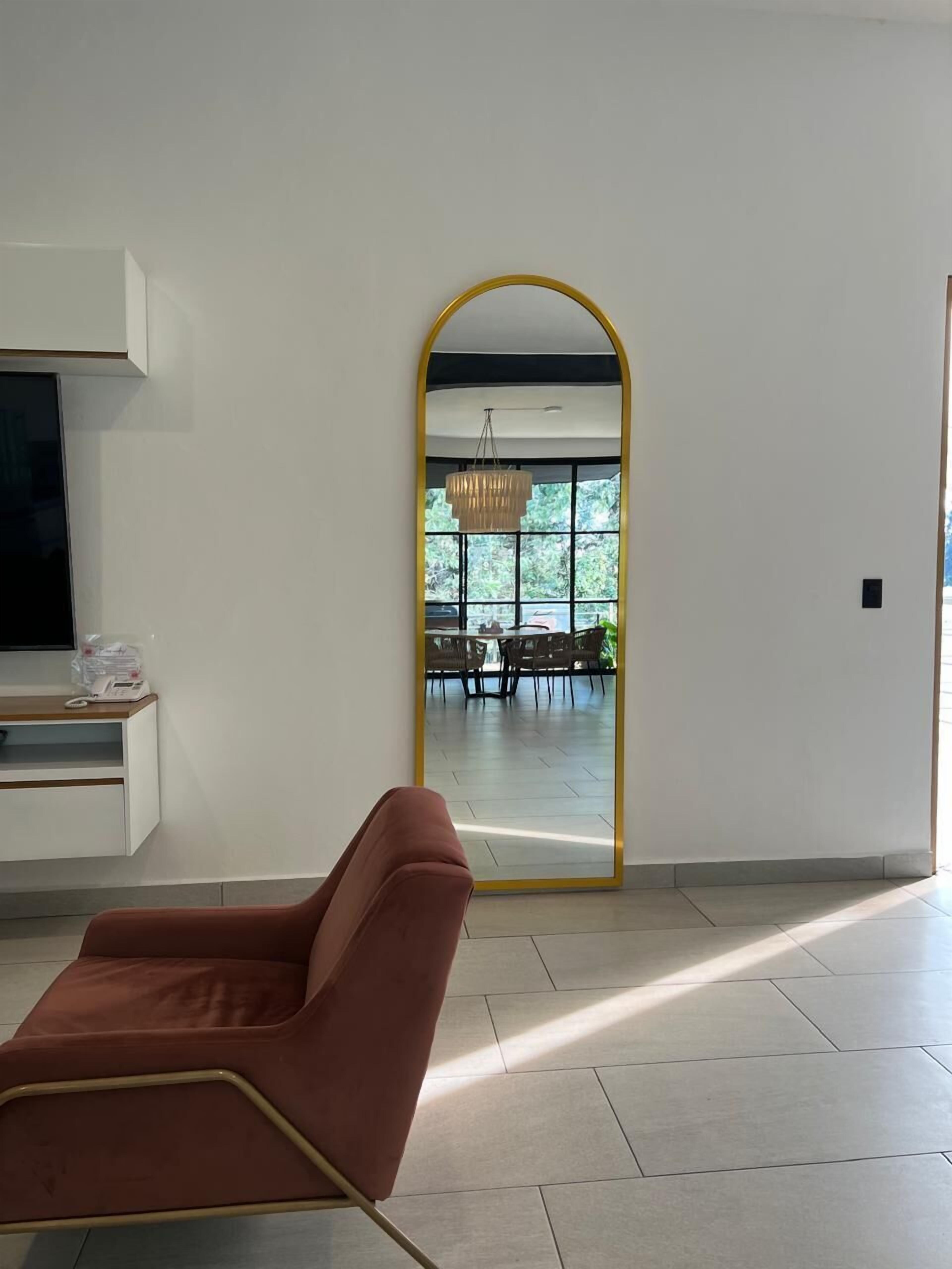 Ein modernes Wohnzimmer mit einem großen Spiegel, einem Fernseher und einem roten Sessel.