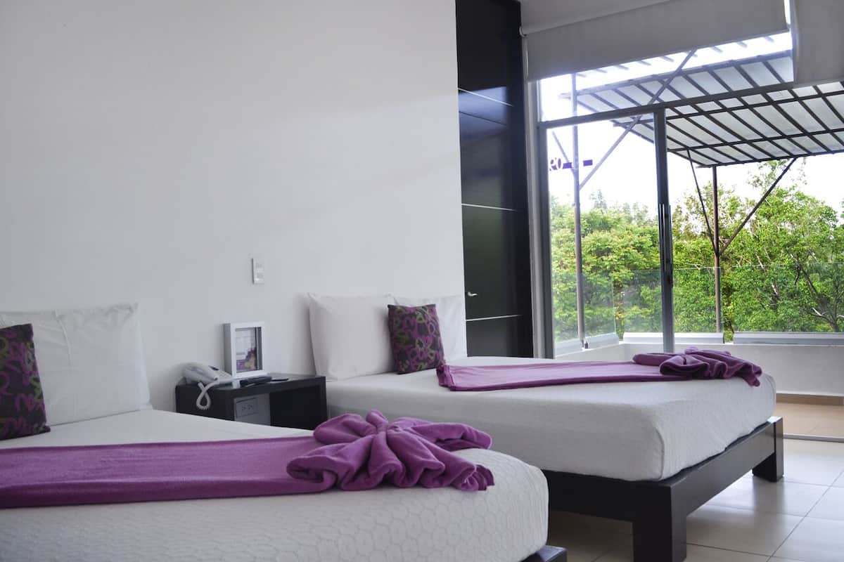 Ein modernes Hotelzimmer mit zwei Betten, einem großen Fenster und einem Balkon mit Blick auf Grünflächen.
