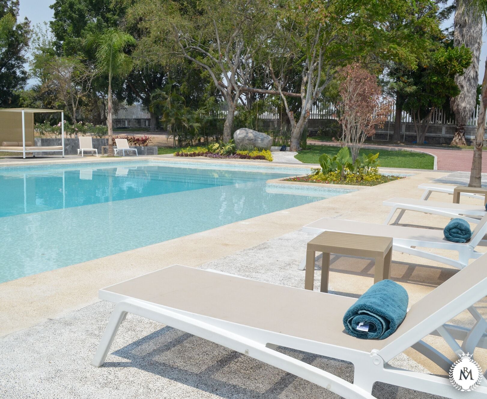 A swimming pool with lounge chairs and a small waterfall feature.