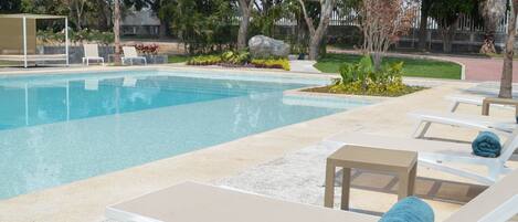 A swimming pool with lounge chairs and a small waterfall feature.
