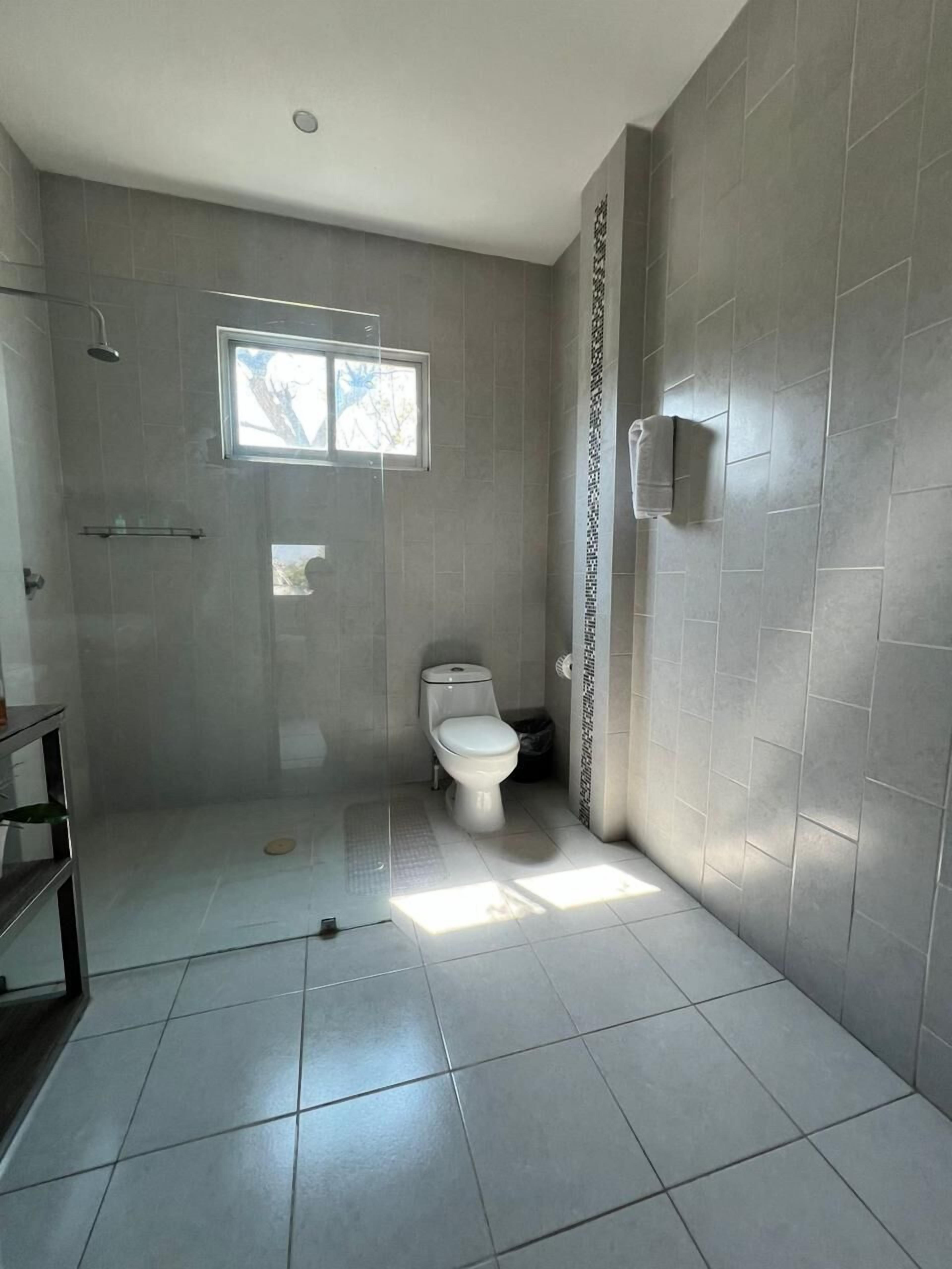 Un baño con inodoro, ducha y ventana.