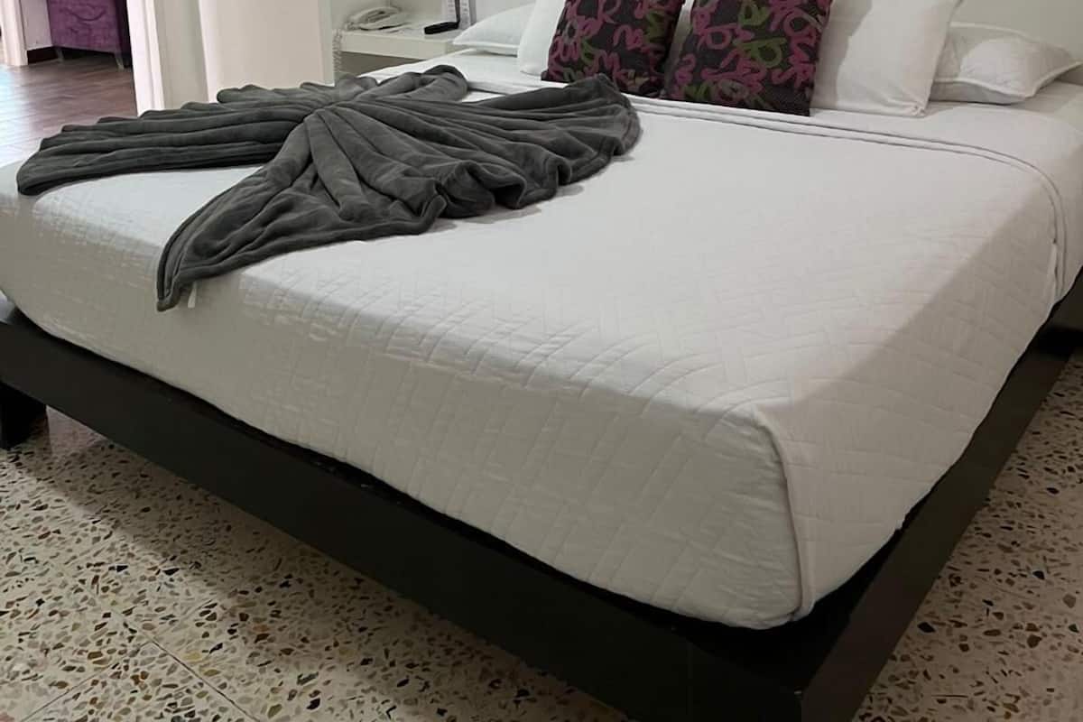 Ein Schlafzimmer mit einem großen Bett, weißen Wänden und einer eingebauten Ablagefläche.