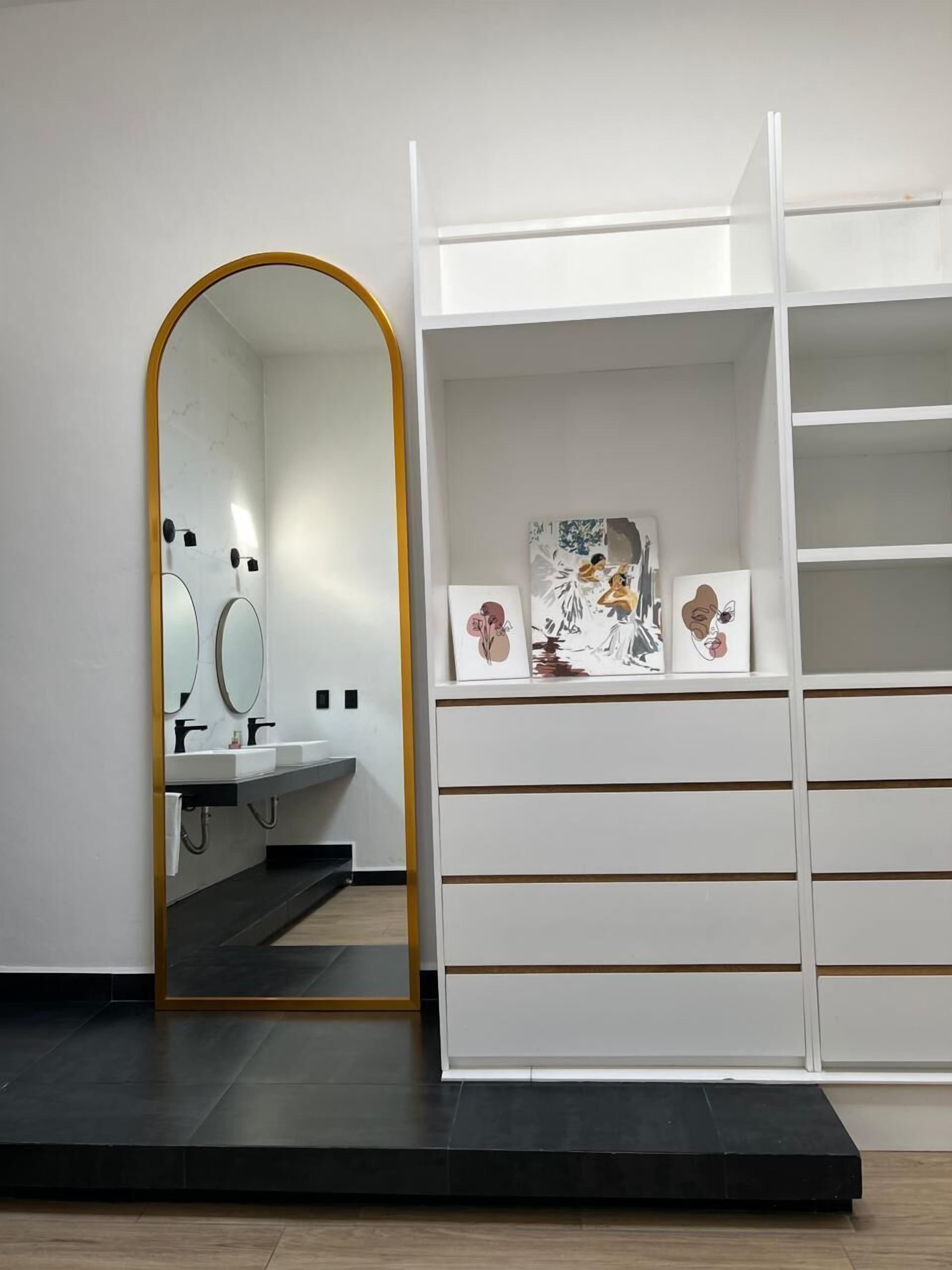 Ein modernes Badezimmer mit Waschtisch, zwei Spiegeln und einer weißen Ablage mit Dekoration.