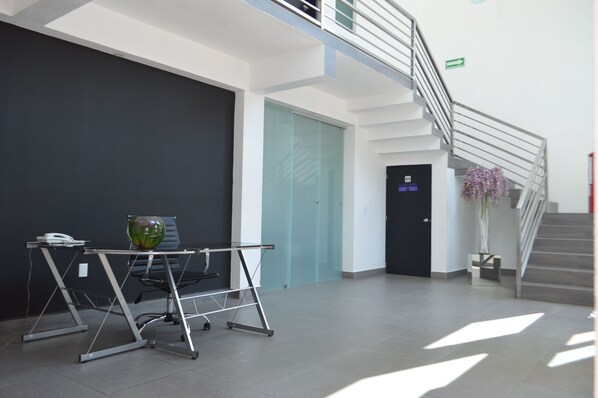A modern office space with a glass table, office chair, and a vase with flowers. - Rancho Macloy Hotel Spa & Social Events (Yautepec)