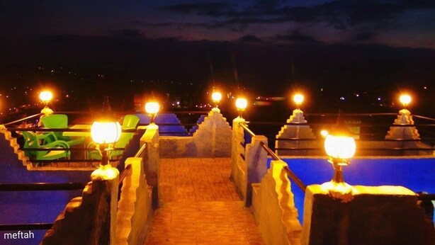 A nighttime view of a rooftop terrace with a pathway leading to a pool area, illuminated by multiple lights. - Riad Antek (Chefchaouen)