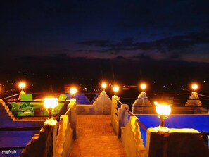 A nighttime view of a rooftop terrace with a pathway leading to a pool area, illuminated by multiple lights. - Riad Antek (Chefchaouen)