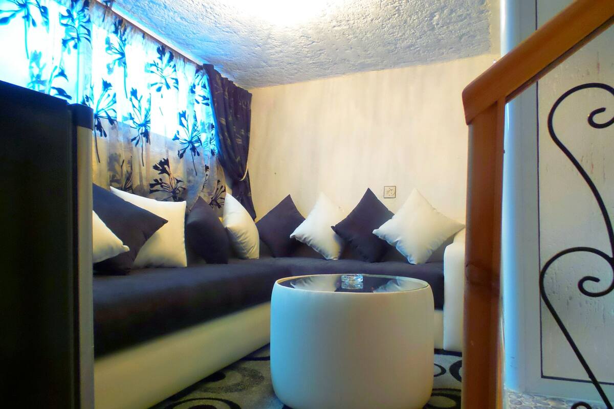 A living room with a sofa, cushions, a coffee table, and patterned carpet.
