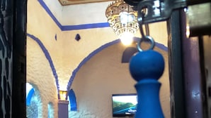 A room with a curved sofa, a television mounted on the wall, and a decorative blue object hanging from the ceiling. - Riad Antek (Chefchaouen)