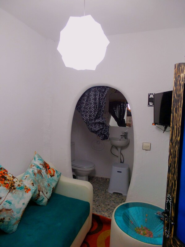 A compact room with a bed, a small sink, and a toilet. - Riad Antek (Chefchaouen)