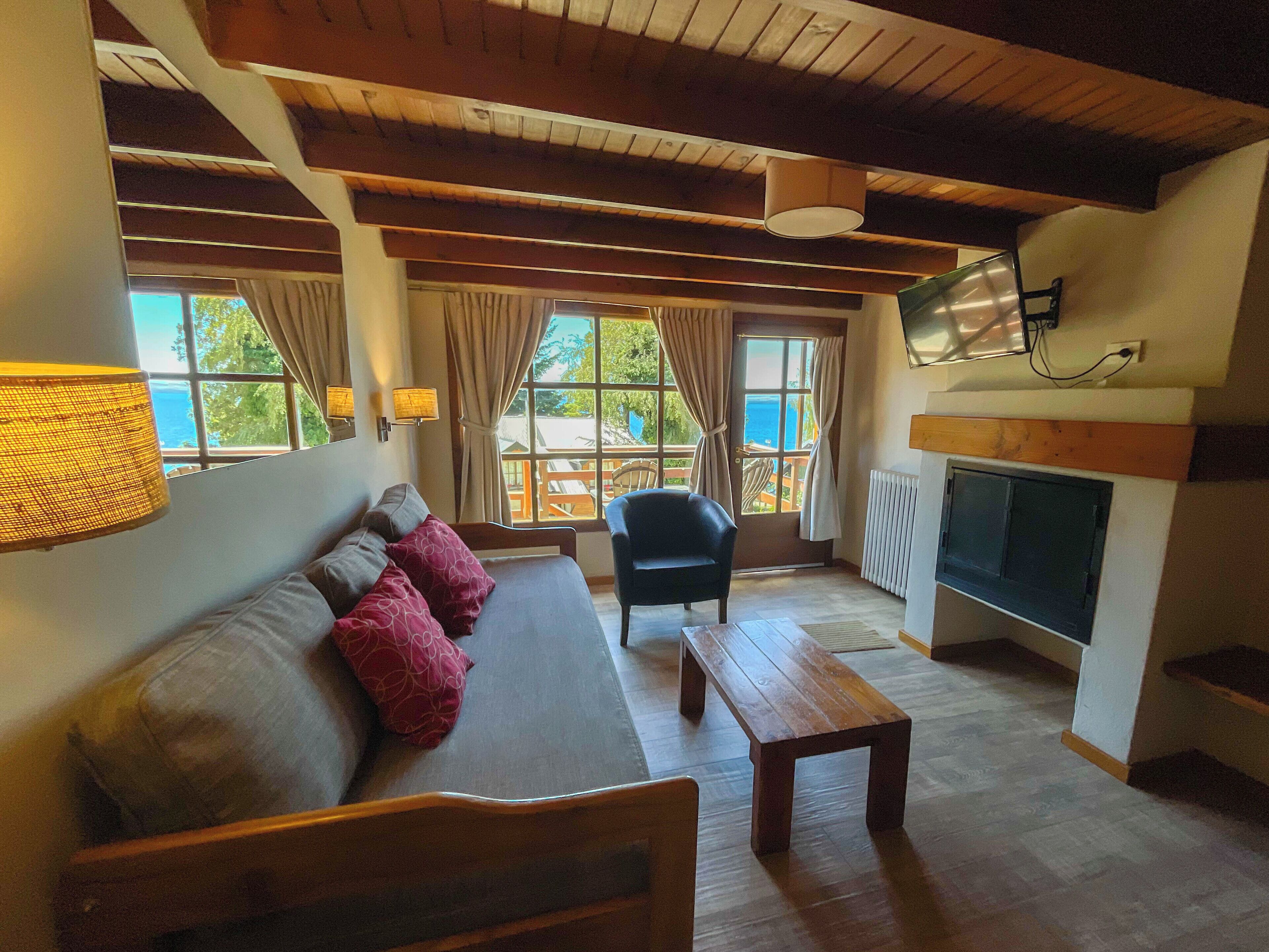 Una sala de estar acogedora con un sofá, un banco de madera, un televisor y una ventana con cortinas.